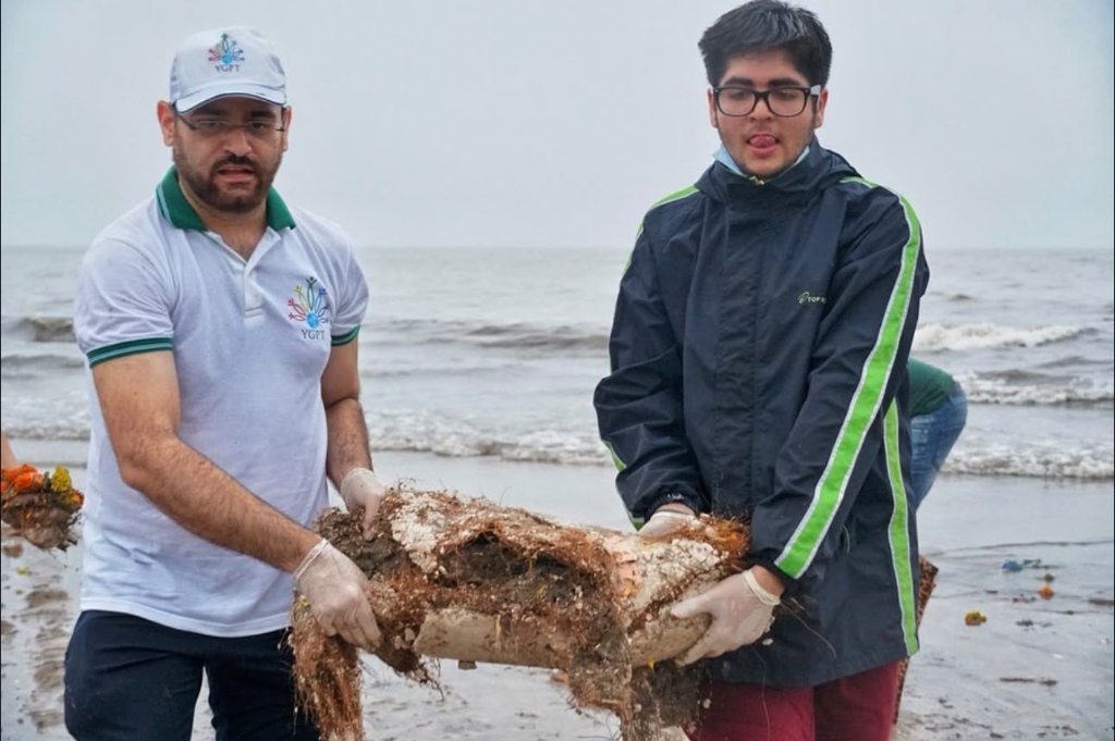 Two volunteers lifting washed-up debris off the shoreline