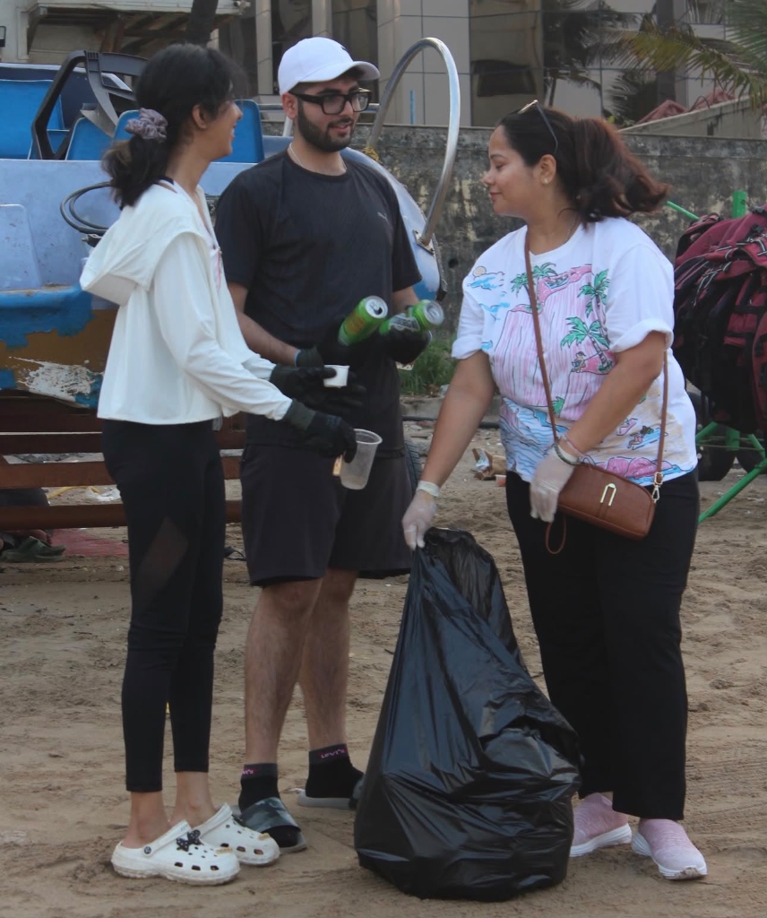 Volunteers collecting waste into black trash bags on the beach